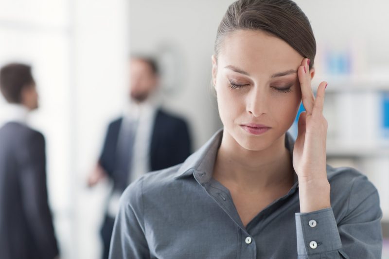 woman placing hand on head during migraines